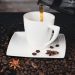 Pouring coffee into a white cup surrounded by coffee beans.