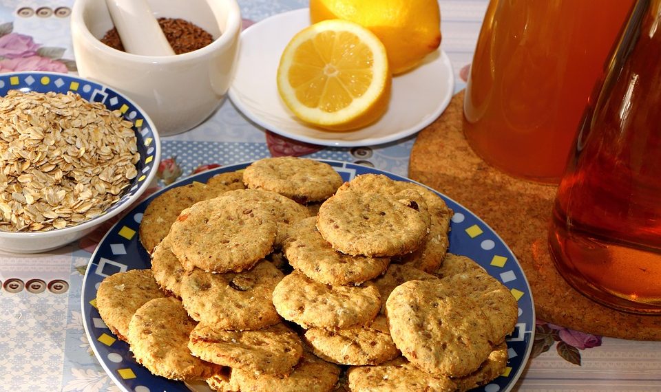 Oatmeal cookies on a plate with lemons and honey ingredients.