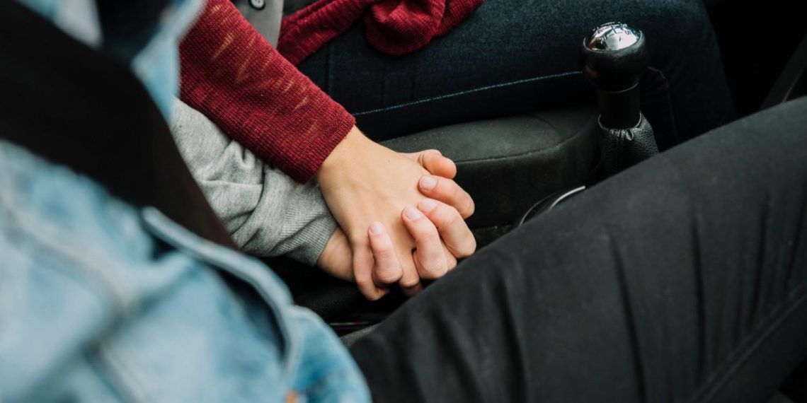 Couple holding hands in a car, expressing love and connection.