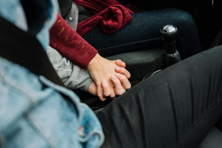 Couple holding hands in a car, expressing love and connection.