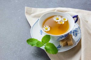 Chamomile tea with fresh mint and sugar cubes on a saucer.