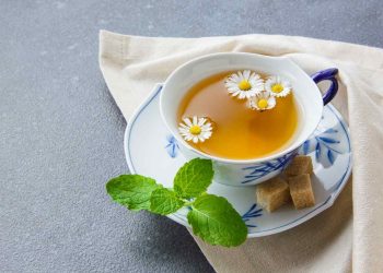 Chamomile tea with fresh mint and sugar cubes on a saucer.