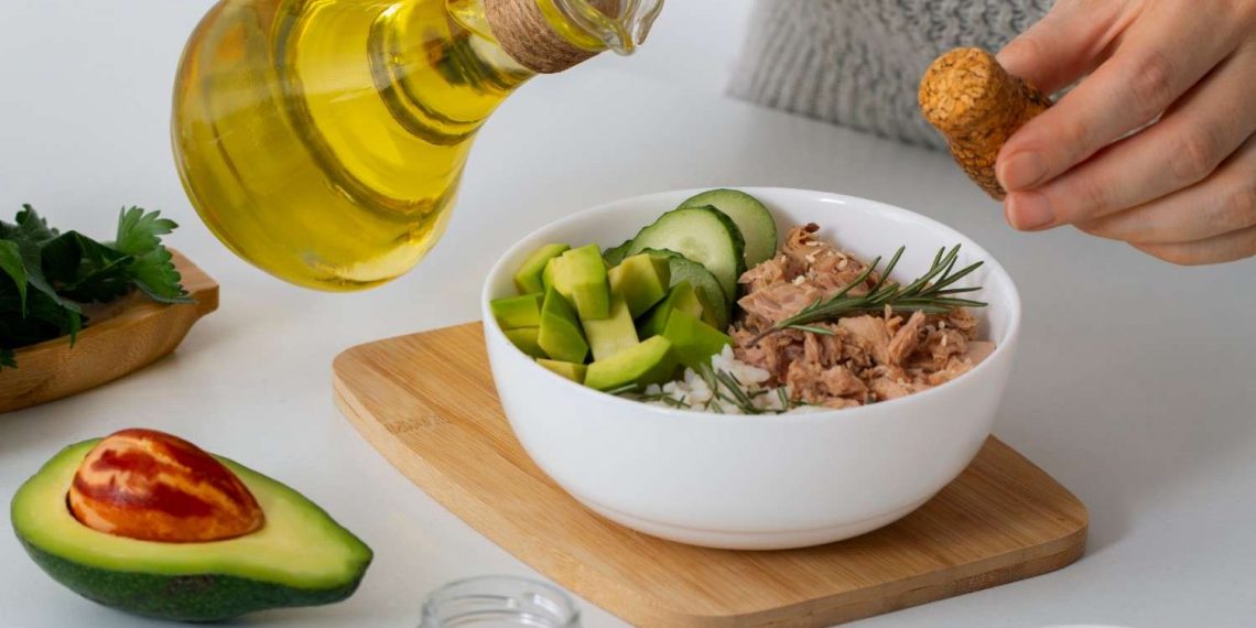 Pouring olive oil over tuna and avocado salad.