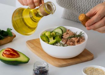Pouring olive oil over tuna and avocado salad.