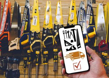 Hand holding phone with tools and delivery app in hardware store.