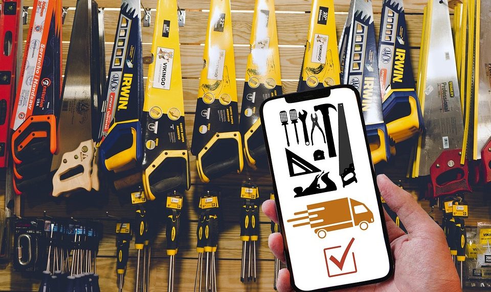 Hand holding phone with tools and delivery app in hardware store.