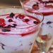 A delicious dessert in a glass, featuring creamy yogurt topped with mixed berries and a vibrant berry sauce.
