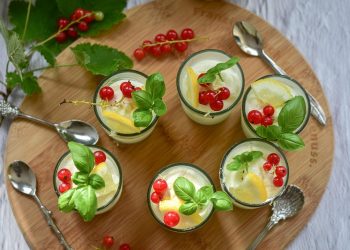 Fresh desserts garnished with red currants and basil leaves.