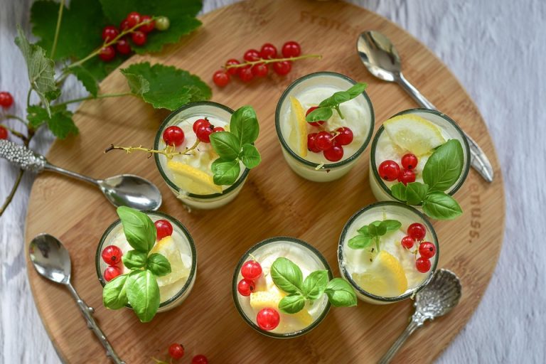 Fresh desserts garnished with red currants and basil leaves.