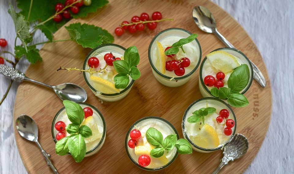 Fresh desserts garnished with red currants and basil leaves.