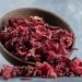 Dried hibiscus petals spilling from a wooden bowl.