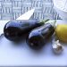 Eggplants, lemon, and garlic on a cutting board with knives.