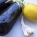 Eggplants with water droplets beside a lemon and garlic.