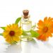 Oil bottle with calendula flowers on white background.