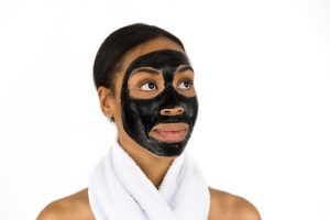 Woman with black face mask and towel around neck.