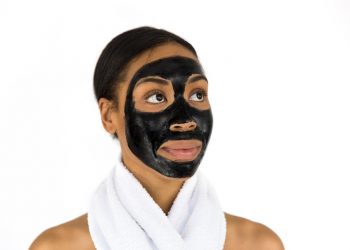 Woman with black face mask and towel around neck.