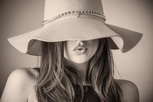 Woman wearing a stylish wide-brimmed hat with chain detail.