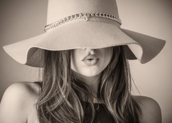 Woman wearing a stylish wide-brimmed hat with chain detail.