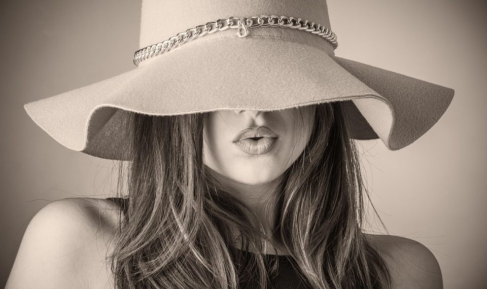 Woman wearing a stylish wide-brimmed hat with chain detail.