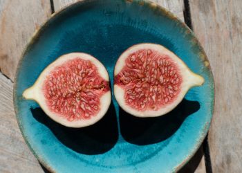 Halved figs in a blue bowl on a wooden table.