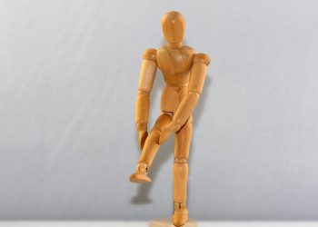 Wooden mannequin posing on one leg.