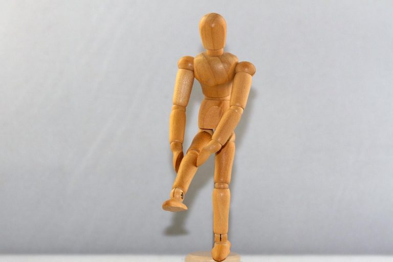 Wooden mannequin posing on one leg.