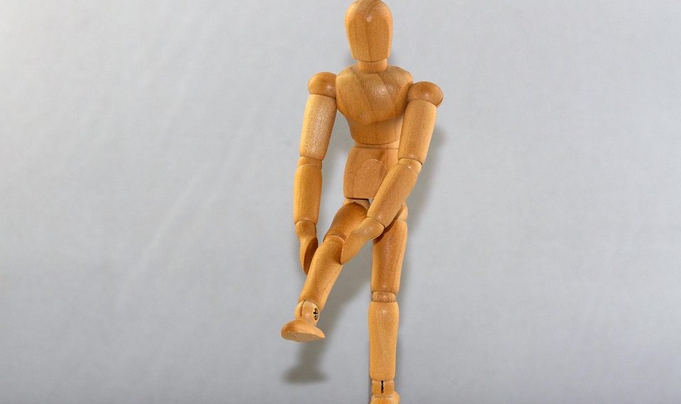 Wooden mannequin posing on one leg.
