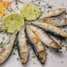 Grilled sardines garnished with lime slices and herbs.
