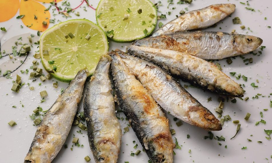 Grilled sardines garnished with lime slices and herbs.