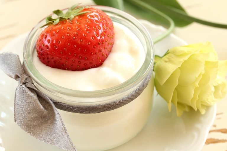 Strawberry sits atop creamy yogurt in a decorative jar.