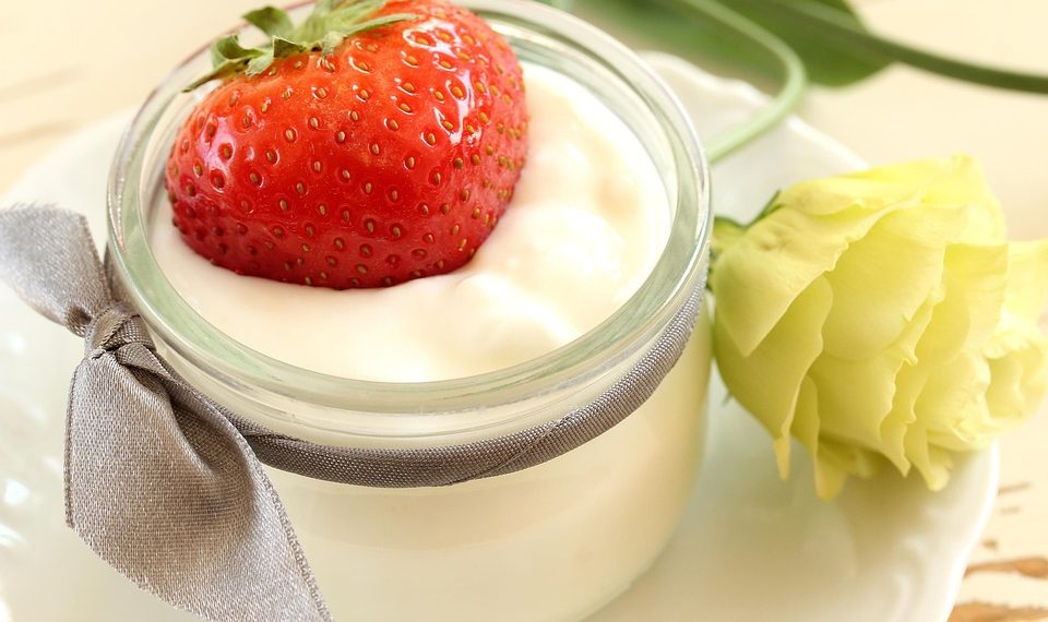 Strawberry sits atop creamy yogurt in a decorative jar.