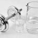 Dumbbell beside a jug and glass of water, promoting fitness balance.