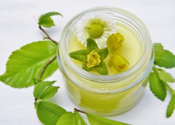 Herbal salve in a jar with fresh flowers and leaves.