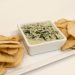 Creamy spinach dip with pita chips on a platter.