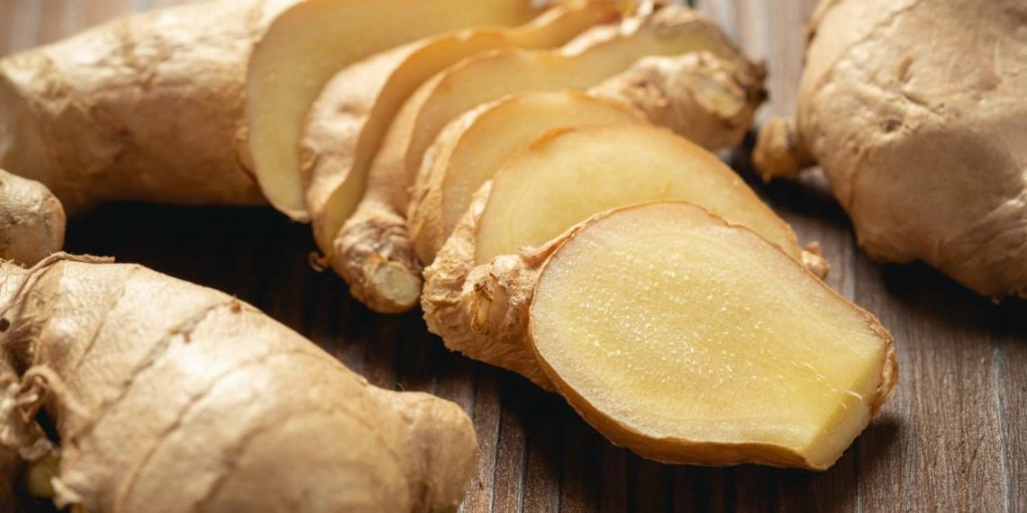 Sliced fresh ginger on a wooden table.