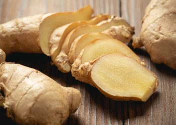 Sliced fresh ginger on a wooden table.