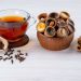 Tea with filled biscuit cups, cloves, and cinnamon sticks.