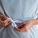 Tying the waist of a medical gown securely for protection.