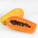 Whole and sliced papaya with seeds on a white background.