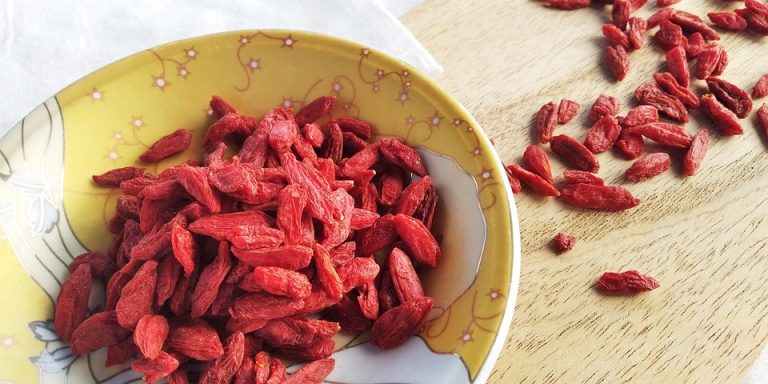 Bowl of dried goji berries on wooden table.