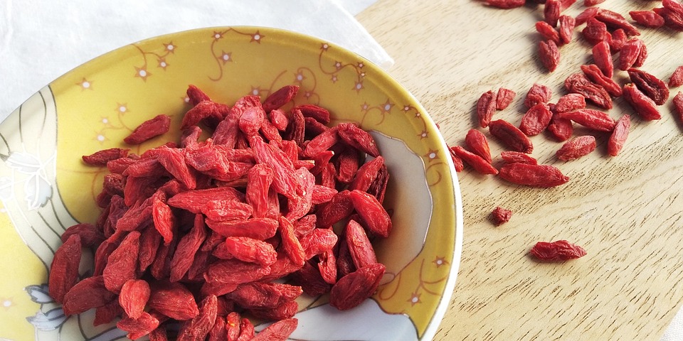 Bowl of dried goji berries on wooden table.