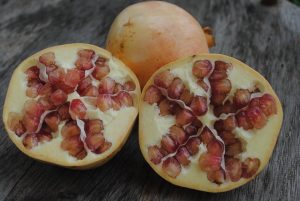 Halved pomegranates with red seeds on a wooden table.