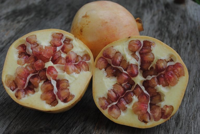 Halved pomegranates with red seeds on a wooden table.