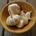 Garlic cloves in a wooden bowl on a rustic table.