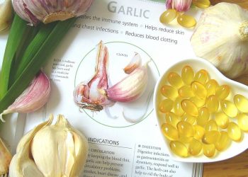Garlic bulbs and supplement capsules on a health benefits page.