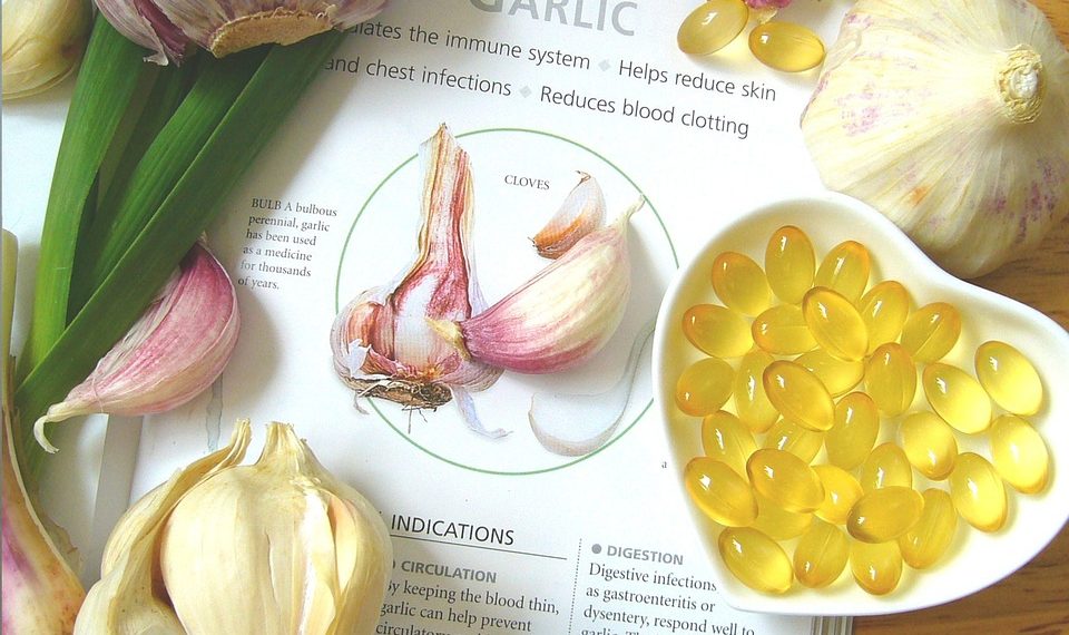Garlic bulbs and supplement capsules on a health benefits page.