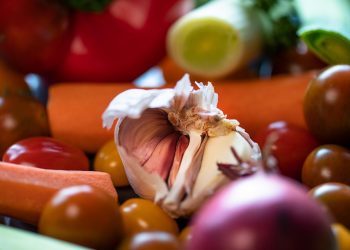 Garlic bulb surrounded by fresh vegetables.