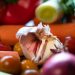 Garlic bulb surrounded by fresh vegetables.