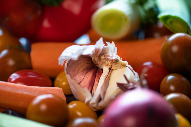 Garlic bulb surrounded by fresh vegetables.