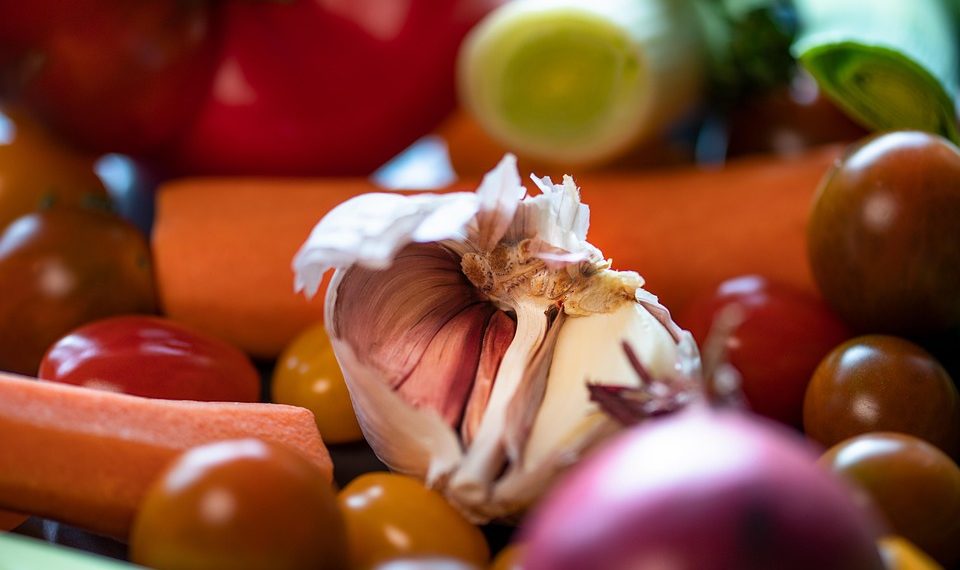 Garlic bulb surrounded by fresh vegetables.